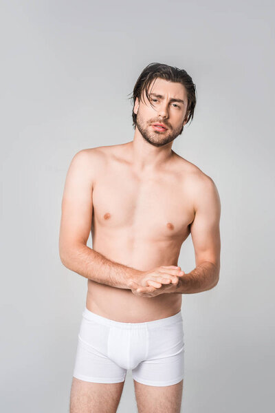 портрет вдумчивого человека в белых трусах, изолированных на сером
