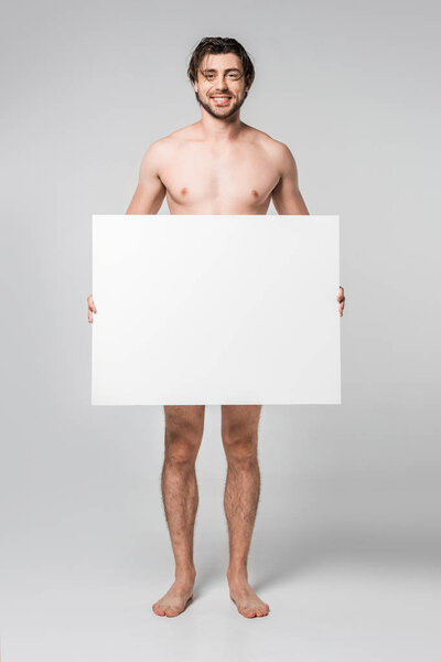 smiling handsome naked man holding blank banner on grey background