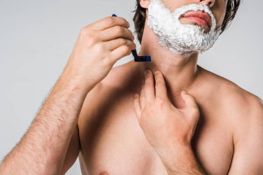 cropped shot of shirtless man with foam on face shaving beard isolated on grey clipart