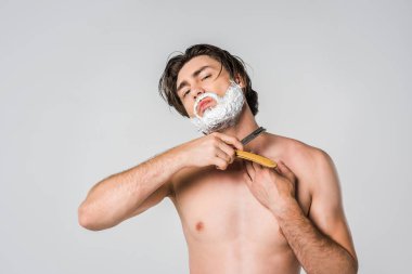 portrait of shirtless man with foam on face shaving beard isolated on grey clipart