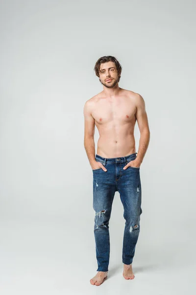 身穿牛仔裤的年轻裸男男子手放在灰色背景的口袋里 — 图库照片