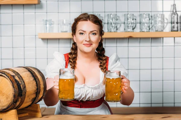 Lächelnde Oktoberfestkellnerin Bayerischer Tracht Gibt Zwei Becher Leichtbier Der Theke — kostenloses Stockfoto