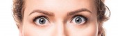 Šokovaný šedé ženské oči při pohledu na fotoaparát, izolované na bílém