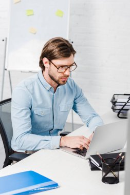 Laptop ile modern ofiste çalışan genç işadamı konsantre