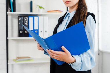Genç işkadını atış modern ofisindeki belgelerin klasörle kırpılmış