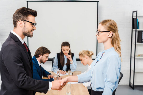 business partners shaking hands during conference at modern office