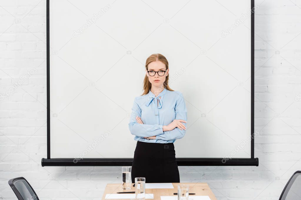 confident young businesswoman with eyeglasses at conference hall looking at camera