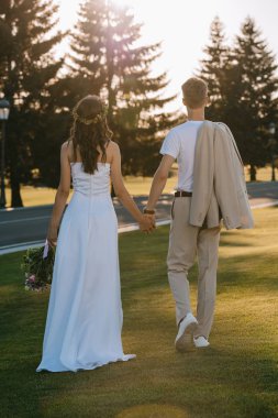 Arkadan Görünüş elele ve açık havada yürüyüş düğün çift