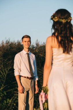 gülümseyen genç damat güzel geline düğün buket ile seyir  