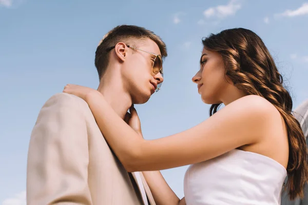 Schönes Hochzeitspaar Umarmt Und Schaut Sich Vor Blauem Himmel — kostenloses Stockfoto