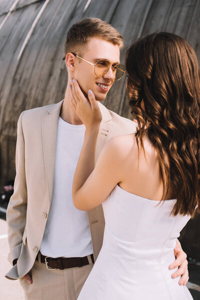 happy elegant wedding couple embracing and looking at each other in city