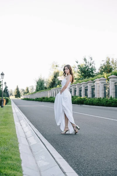 道路の上を歩くウェディング ドレスで美しいエレガントな花嫁  — 無料ストックフォト
