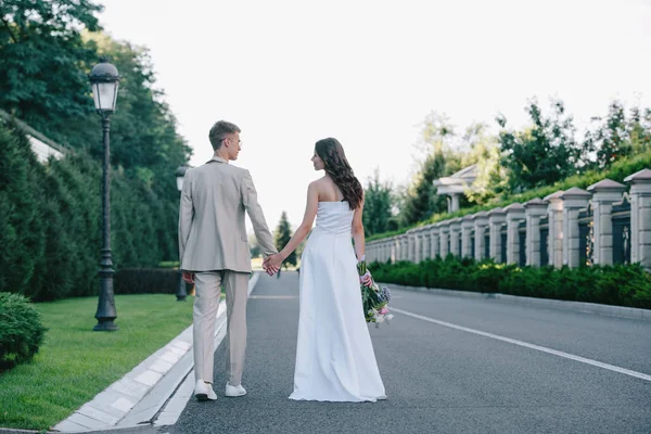 Vista Trasera Novia Novio Tomados Mano Caminando Por Carretera —  Fotos de Stock