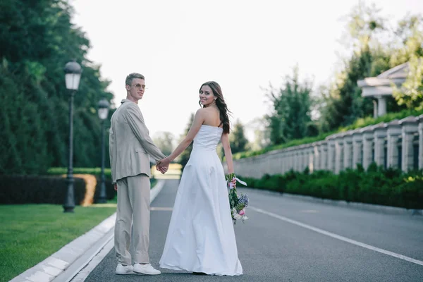 Rückansicht Von Braut Und Bräutigam Die Händchen Halten Auf Der — kostenloses Stockfoto