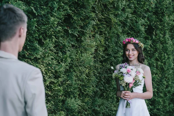 花輪は結婚式のブーケを押しながら新郎を見ての幸せの魅力的な花嫁の選択と集中 — ストック写真