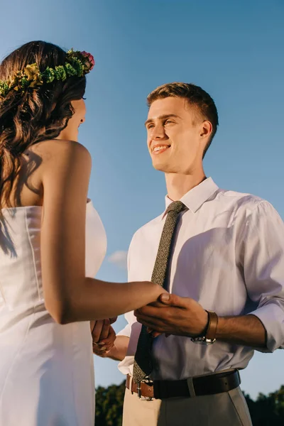 Vista Ángulo Bajo Feliz Joven Pareja Boda Tomados Mano Sonriendo — Foto de stock gratuita