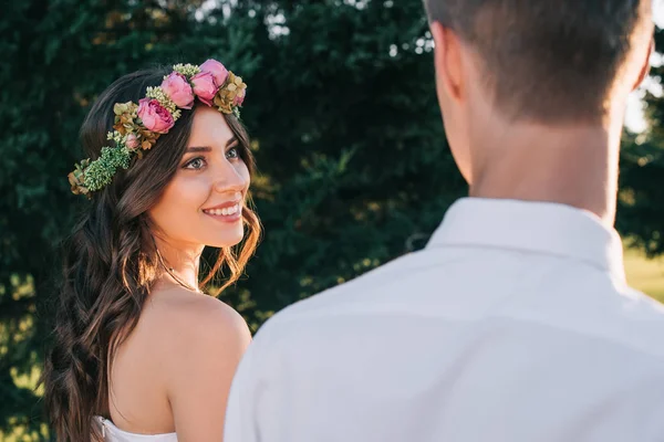 公園で新郎を見て花の花輪で美しい笑顔若い花嫁のクロップ撮影 — ストック写真