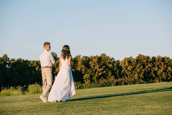 公園を一緒に歩いて美しい若い結婚式のカップルの背面図 — ストック写真