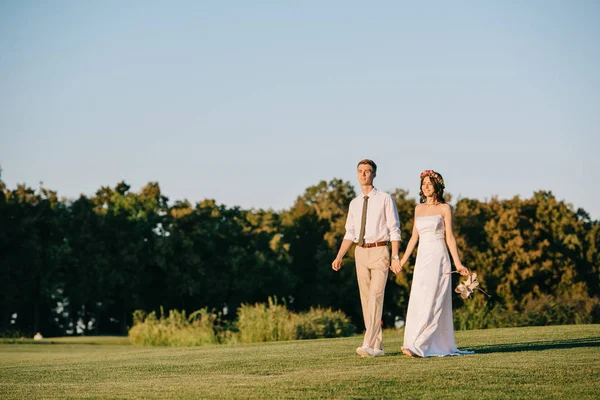 Красива Щаслива Молода Весільна Пара Тримає Руки Ходить Разом Парку — Безкоштовне стокове фото