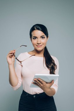 gri izole dijital tablet ile gülümseyen esmer kadın portresi