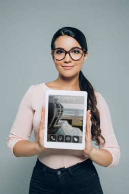 kadın gösteren dijital tablet gri izole bilet satın almak için seyahat cihaz ile