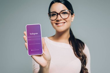 Smartphone instagram cihaz ile sunulması kız gülümseyerek, gri izole