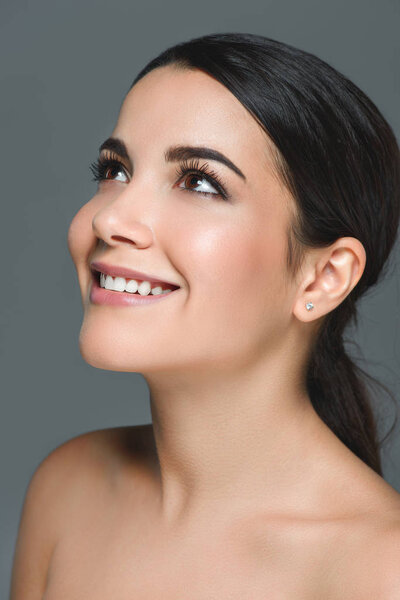 portrait of attractive smiling woman with white teeth looking away isolated on grey