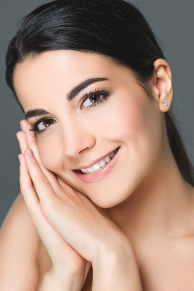 portrait of attractive smiling woman with white teeth looking at camera isolated on grey