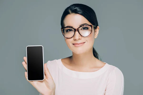 照片中美丽的黑发妇女在眼镜显示智能手机空白屏幕在手上隔离白色 — 图库照片