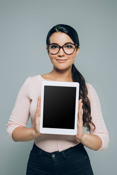 woman showing digital tablet with blank screen, isolated on grey