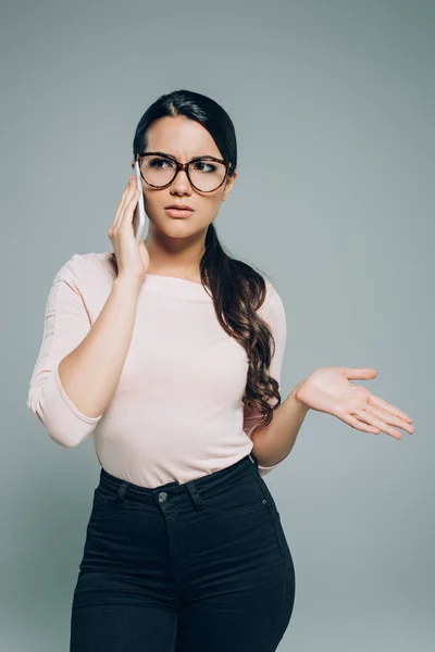 Mujer Confundida Gafas Gestos Hablando Teléfono Inteligente Aislado Gris — Foto de Stock