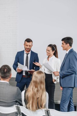 smiling businesspeople talking about documents during training in hub  clipart