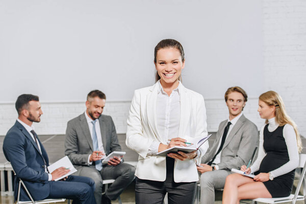 привлекательный бизнес-тренер, стоящий перед бизнесменами на тренинге в хабе
