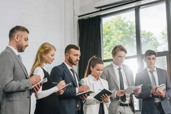 Businesspeople Standing Row Writing Something Notebooks Training Hub — Stock Photo, Image