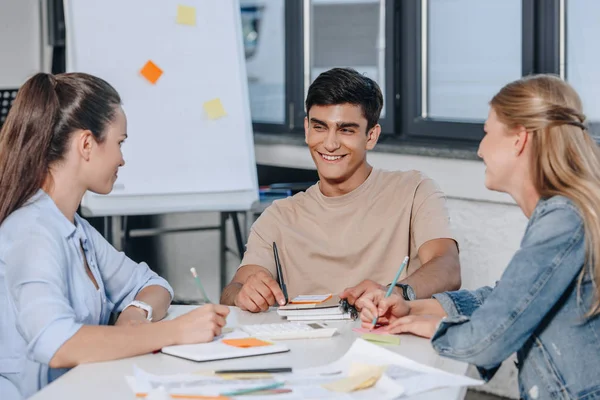 Jovens Empresários Sorridentes Sentados Mesa Durante Reunião Escritório — Fotografia de Stock