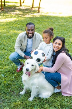 Afrikalı Amerikalı anne ve kızı futbol topu ve köpek Park ile gülümseyen