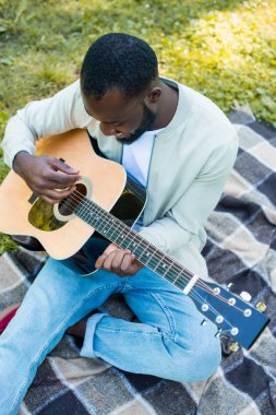 bir Afrikalı-Amerikalı adam parkta akustik gitar çalmak yüksek açılı görünüş