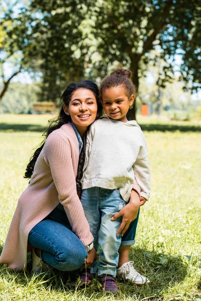 アフリカ系アメリカ人の母娘を抱き締めると 公園でカメラ目線の笑顔 — ストック写真