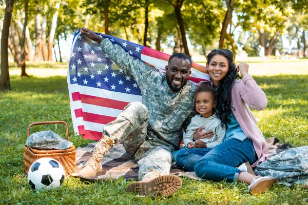在军事制服和家庭持有美国国旗的快乐非洲裔士兵在公园 — 图库照片