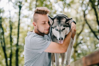 Genç adam kucaklama husky köpek park