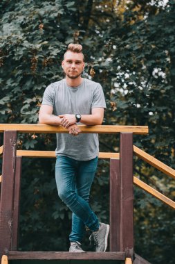 Korkuluk eğilerek ve kamera Park bakarak yakışıklı adam