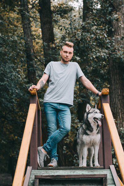 young man posing on stairs with husky dog 