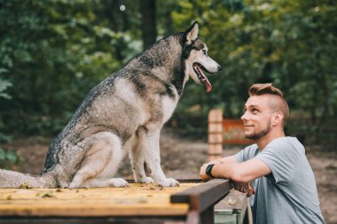 young man looking at siberian husky dog clipart