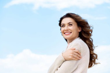 side view of smiling beautiful woman with blue cloudy sky on background clipart