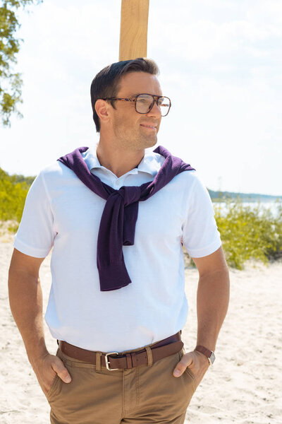 portrait of smiling man in eyeglasses on sandy beach