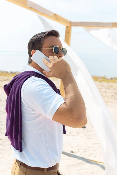 Sidovy Eleganta Mannen Solglasögon Talar Smartphone Sandstrand — Gratis stockfoto