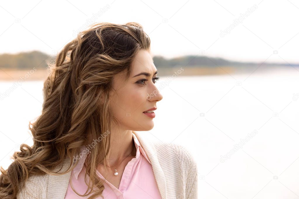 side view of thoughtful woman looking away with sea on background
