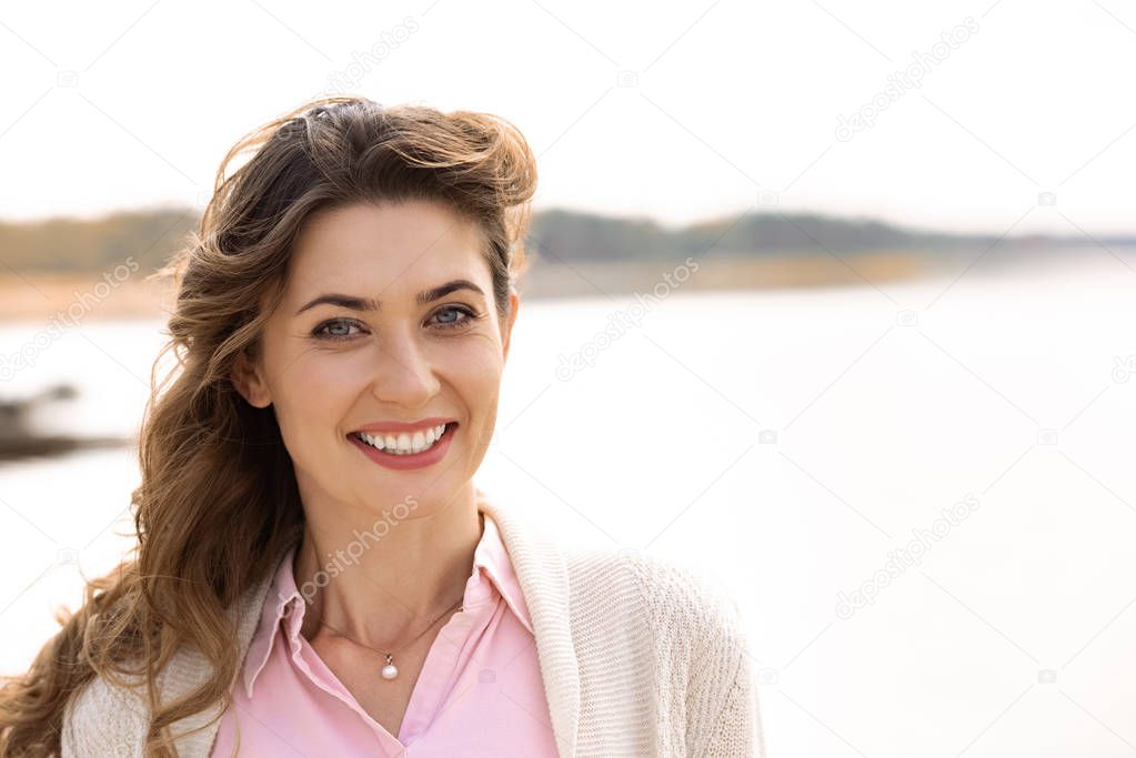 portrait of beautiful smiling woman with looking at camera river on background
