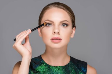 portrait of elegant woman with makeup brush for eyeshadows isolated on grey clipart
