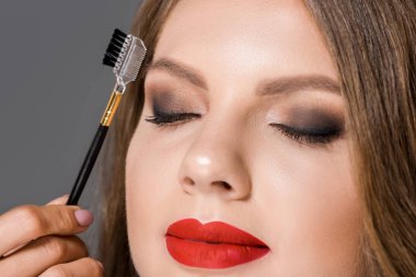kısmi görünümü modeli gözleri ve kaşları için fırça ile makyaj sanatçısı olarak izole gri kapalı